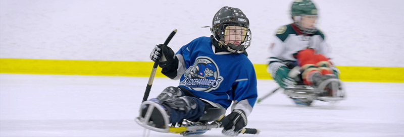 Two children playing sledge hockey